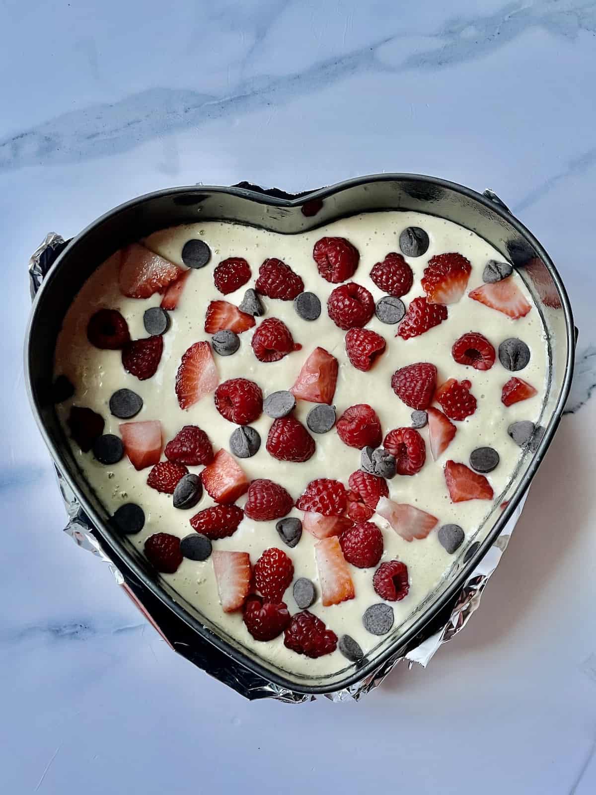 pancake batter topped with fruit in a heart shaped spring form pan