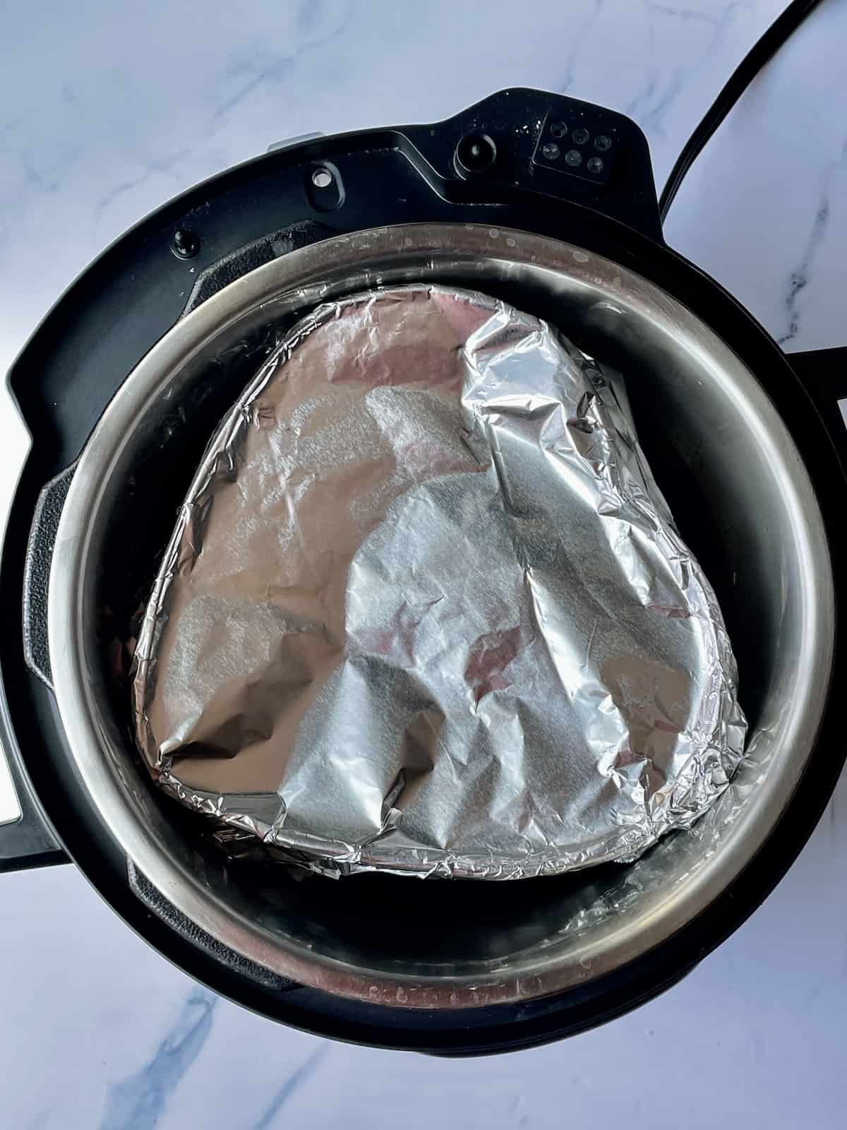 a heart shaped pan wrapped in foil on a trivet in the instant pot