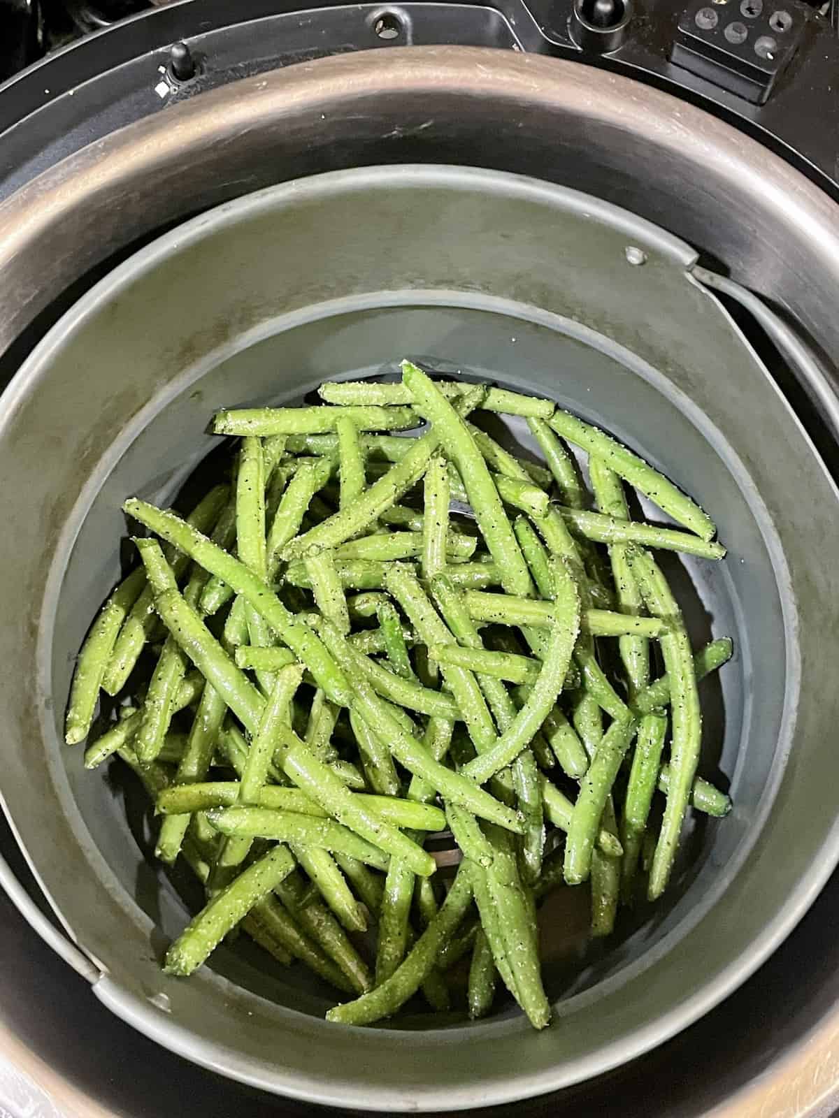 green beans in an air fryer basket before cooking