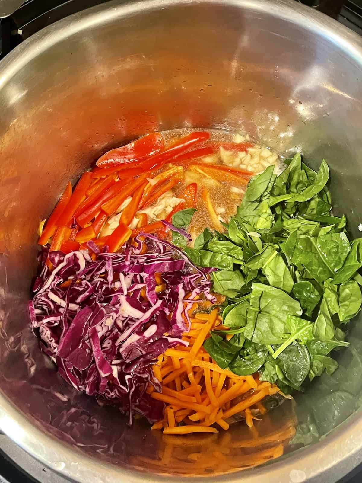 spinach, cabbage, carrots, peppers, and chicken in a pressure cooker
