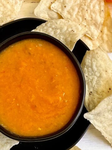 mango habanero salsa in a black bowl surrounded my tortilla chips