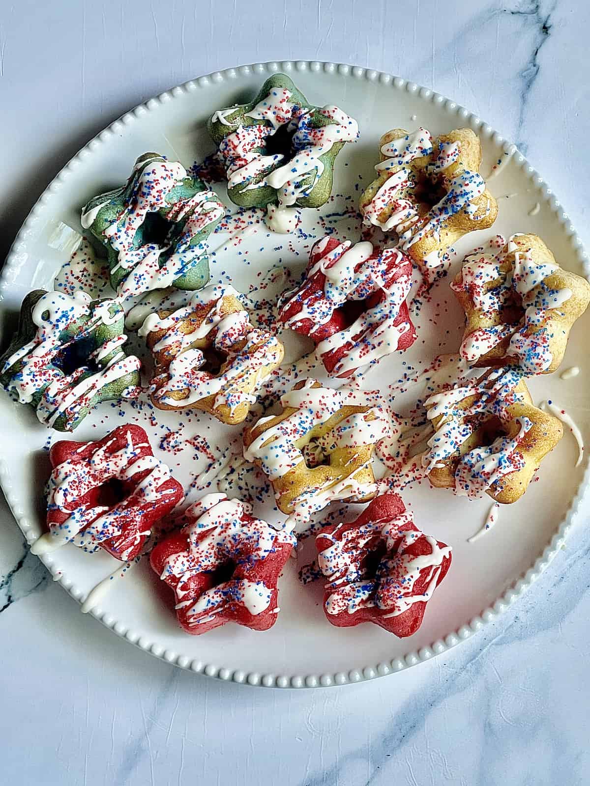 mini patriotic cakes on a white plate with vanilla glaze and sprinkles