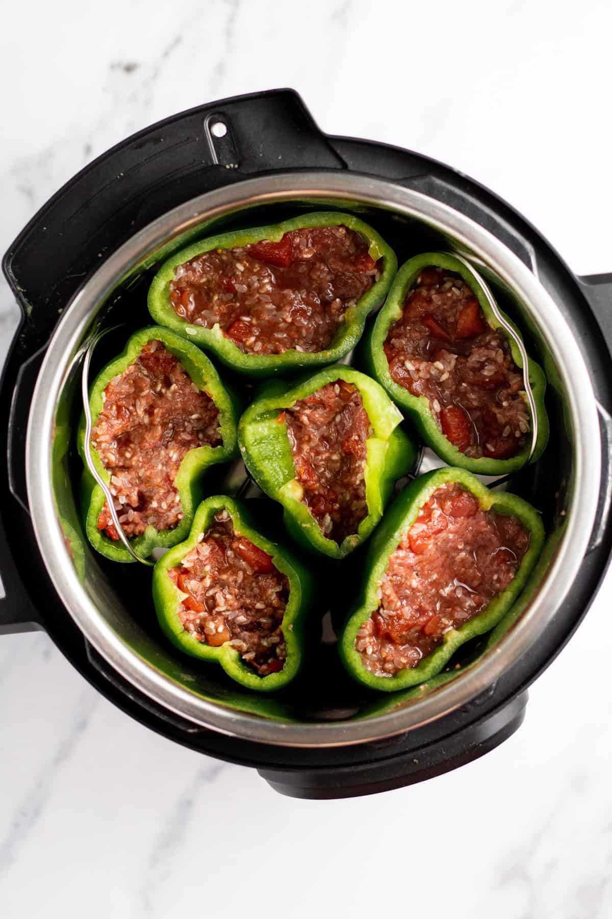 peppers stuffed with ground beef mixture on a trivet in a pressure cooker
