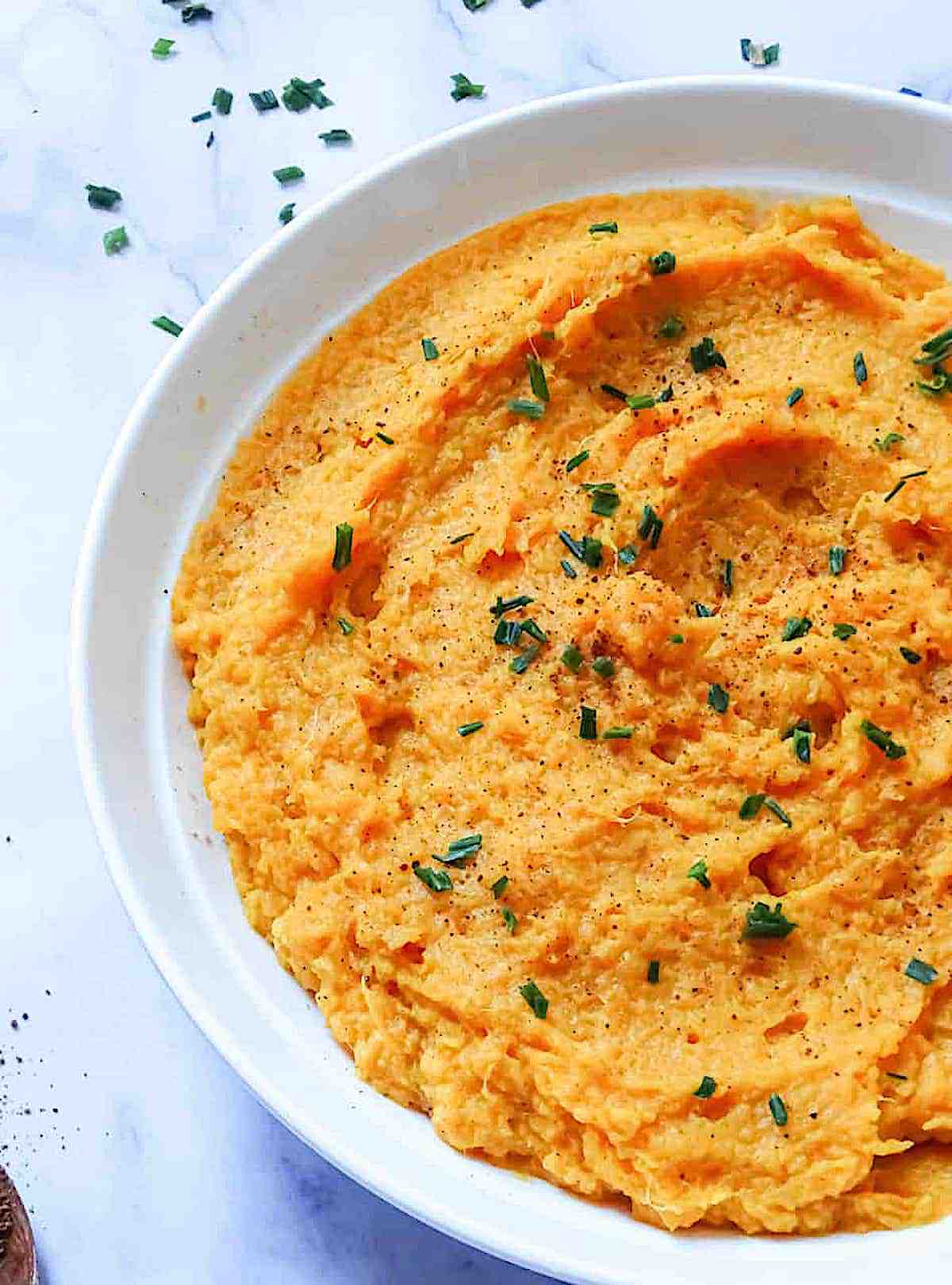 instant pot mashed sweet potatoes in a white bowl with chives