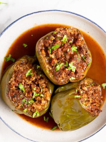 three instant pot stuffed peppers in a bowl with sauce