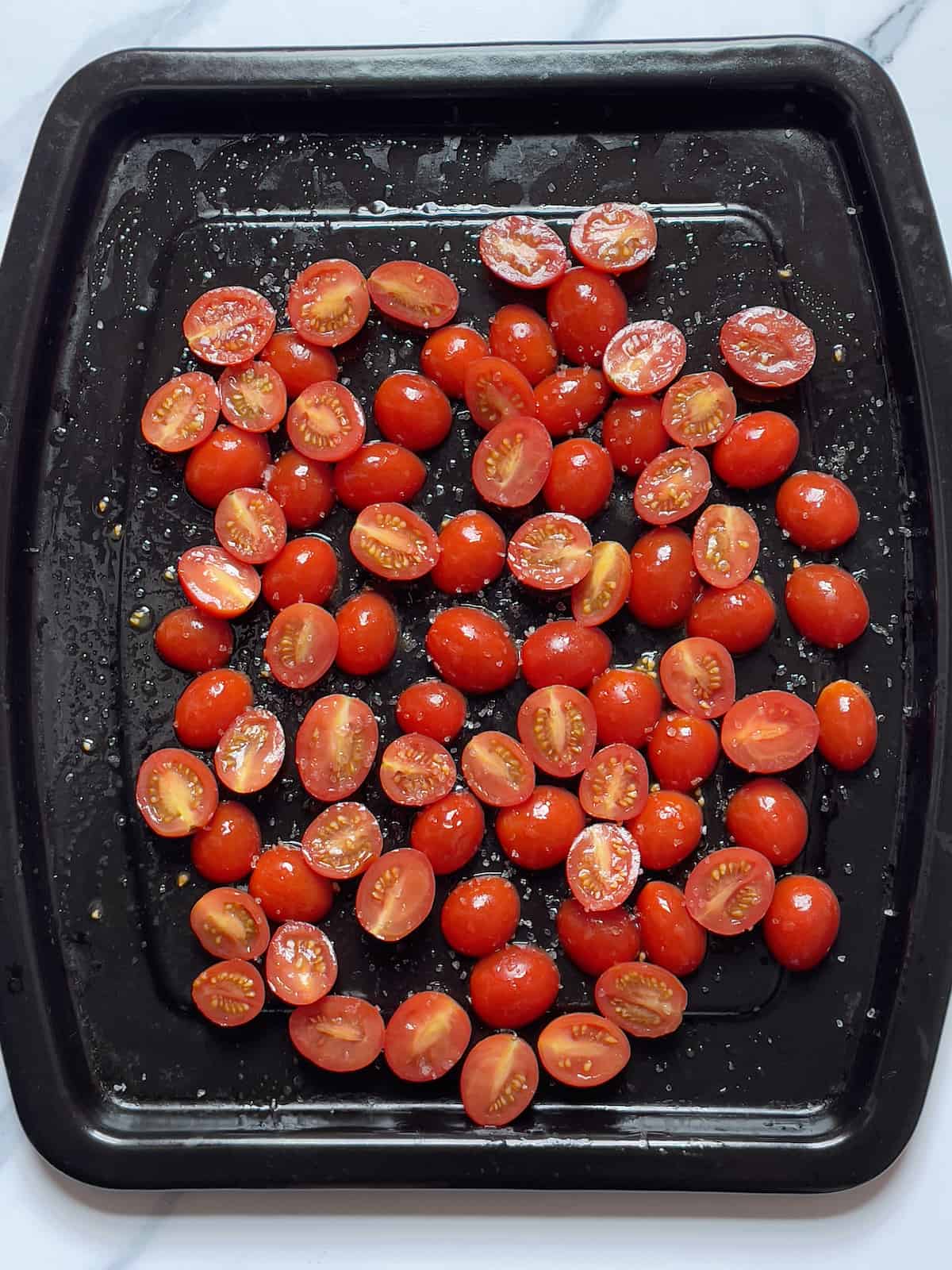 halved cherry tomatoes on a black pan