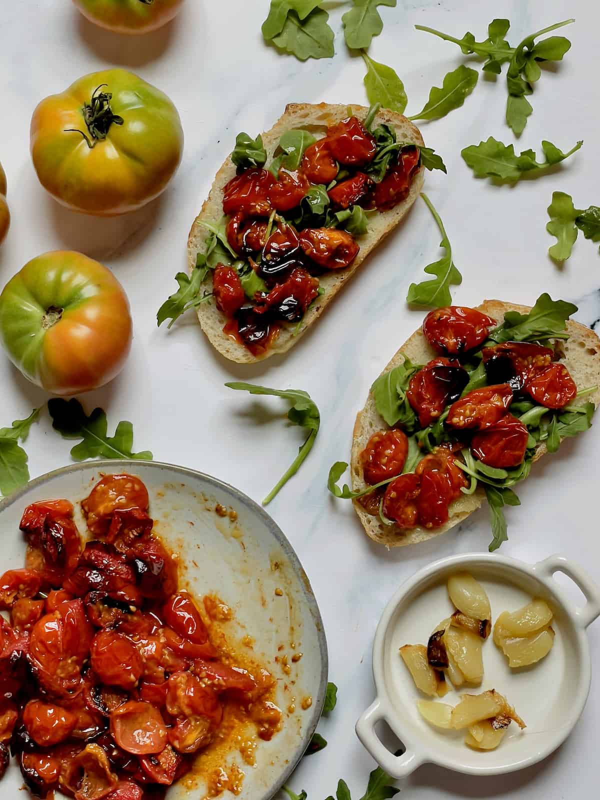 roasted tomatoes, roasted garlic and arugula on 2 slices of french bread, with extra vegetables in dishes