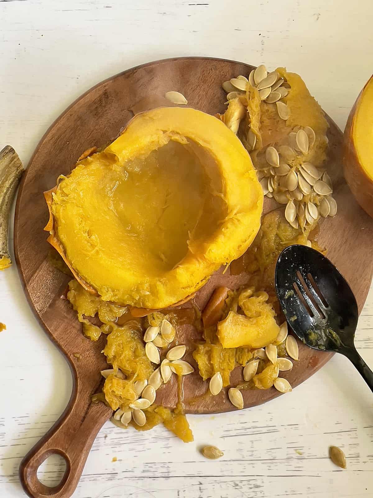 roasted pumpkin on a cutting board with the seeds scooped out