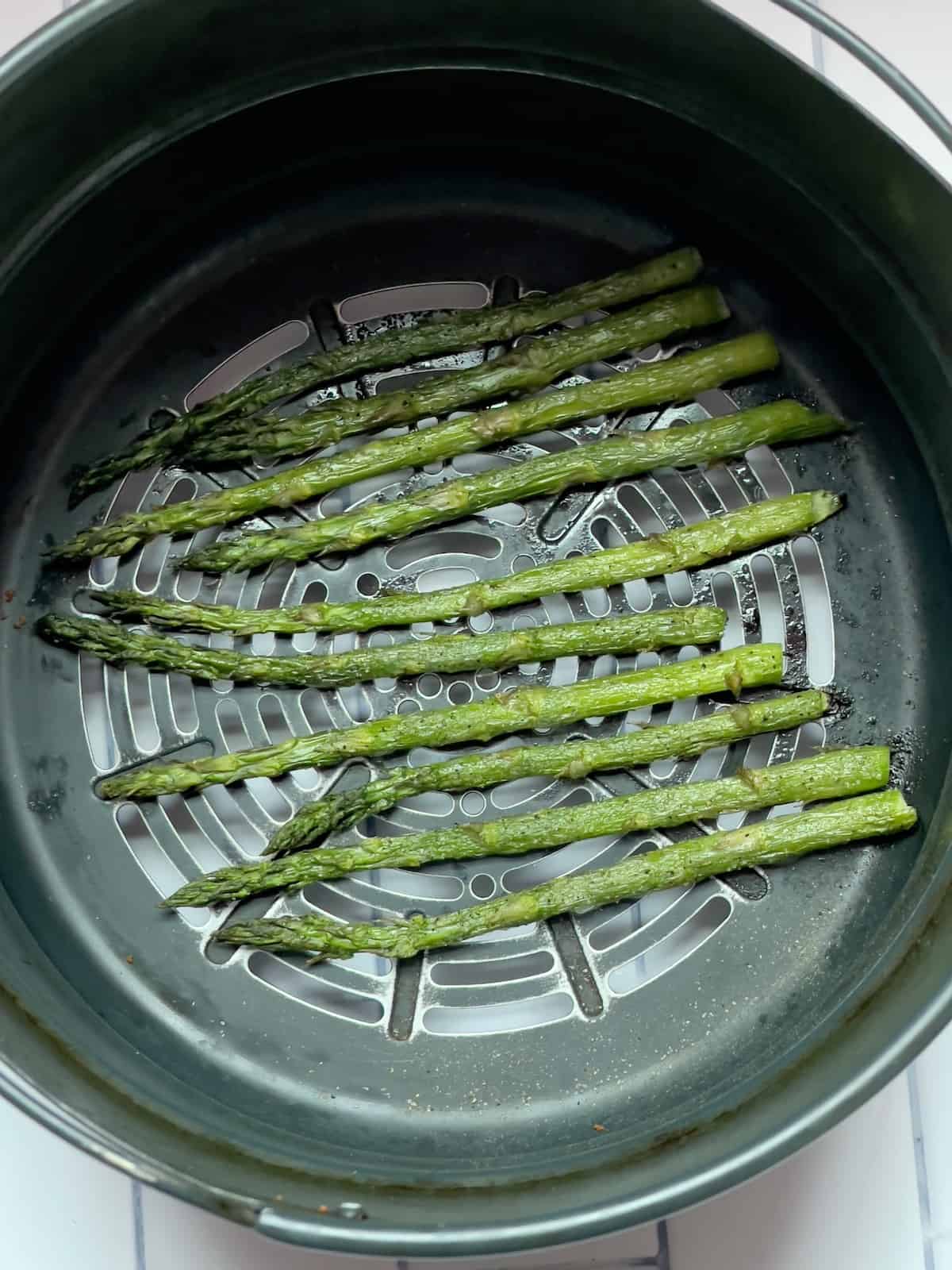 cooked asparagus in an air fryer basket