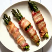 air fried bacon wrapped asparagus on a white plate and white background