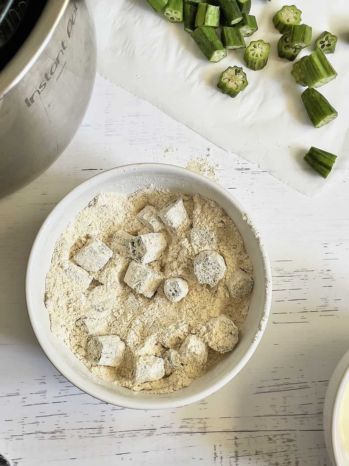 okra slices coated in cornmeal and flour mixture in a bowl