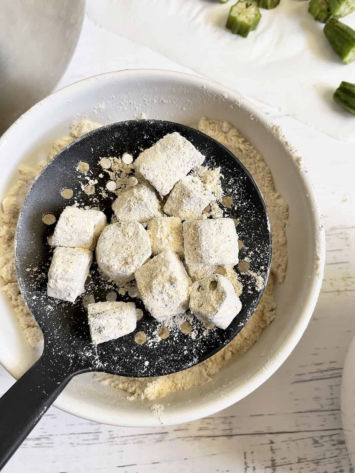 sifting okra breading with a slotted spoon