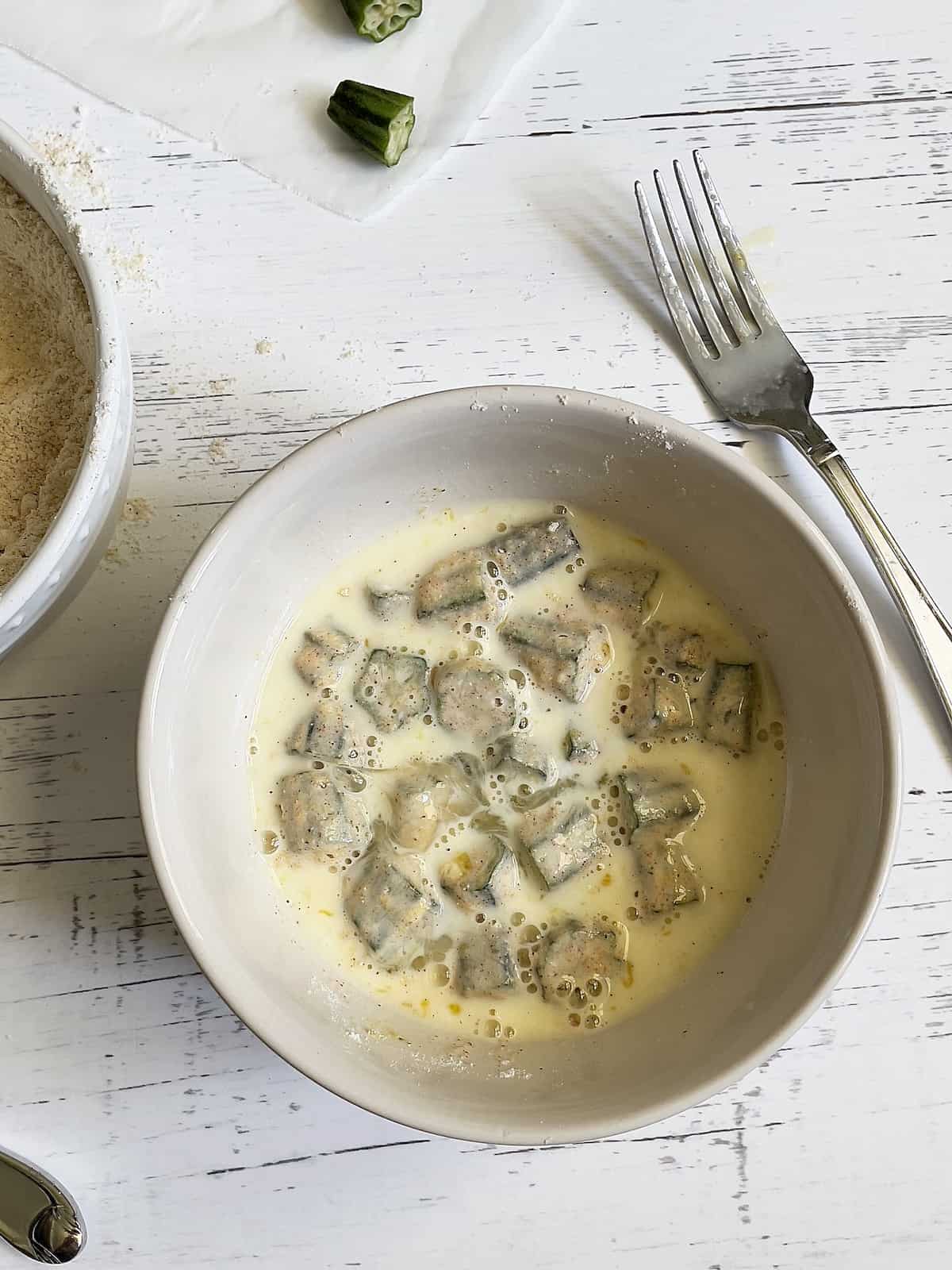 okra in a bowl of buttermilk