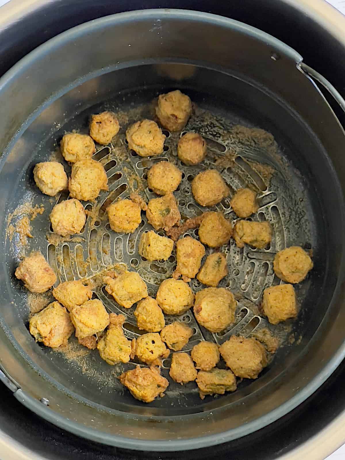 air fried okra in a basket being sprayed with cooking spray