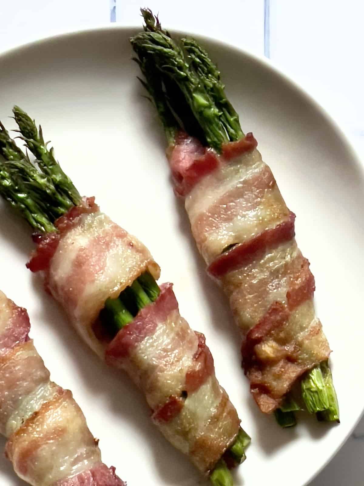 air fryer bacon wrapped asparagus on a white plate