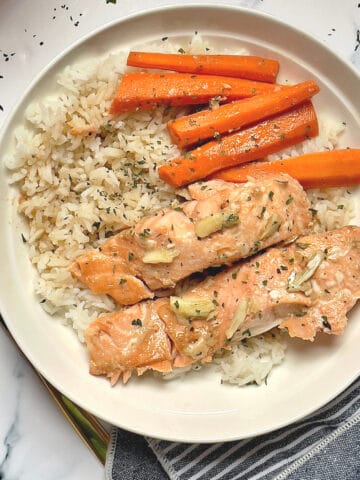 salmon, carrots, and white rice topped with parsley in a white plate