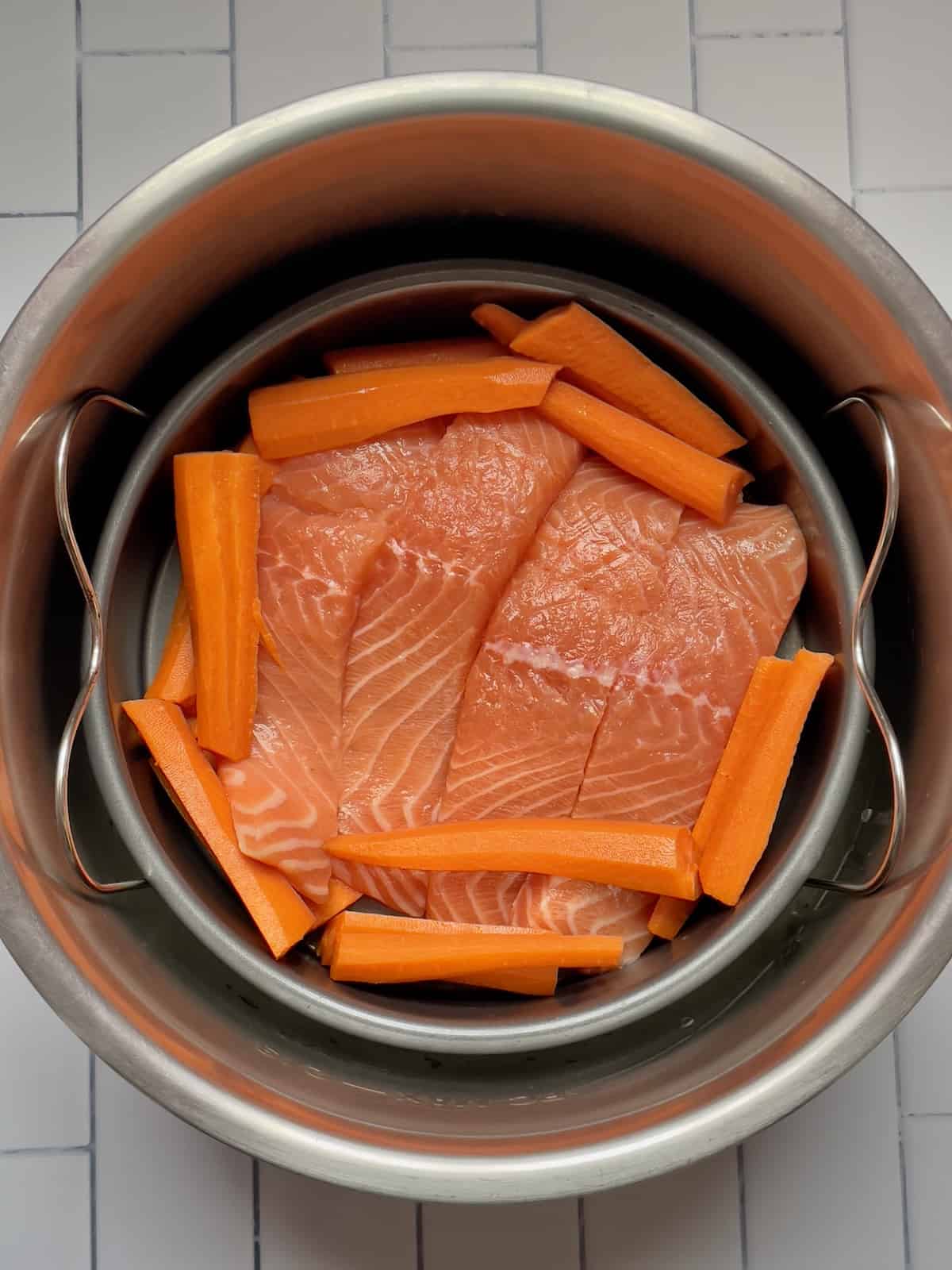 salmon and carrots in a cake pan in a pressure cooker