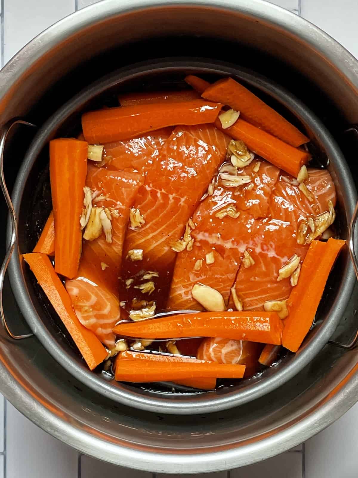 salmon and carrots covered in maple glaze in a cake pan in the instant pot