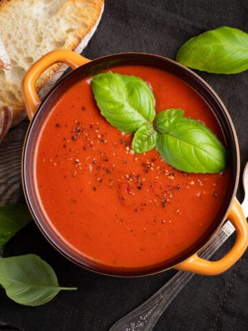 blender tomato soup in a crock topped with basil