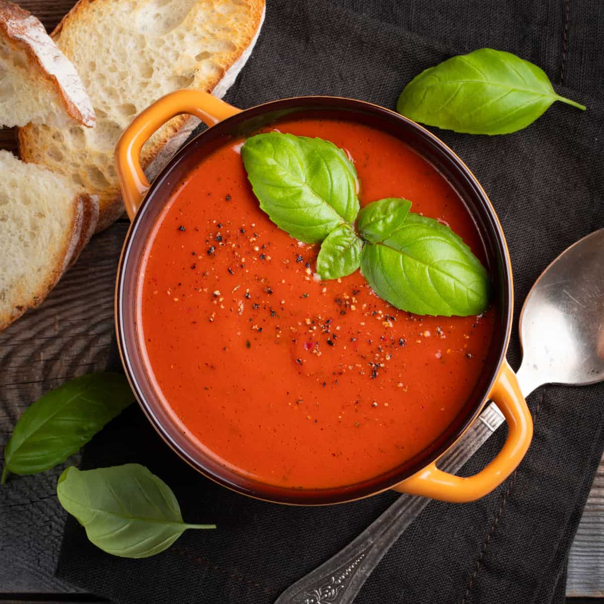 blender tomato soup in a crock topped with basil