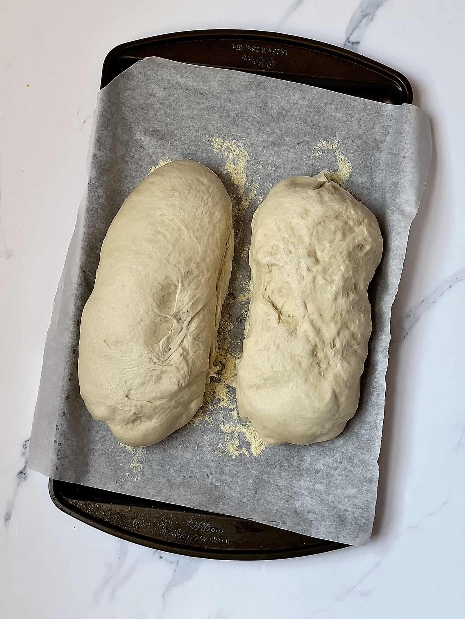 2 risen loaves of dough on a baking sheet