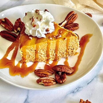 pressure cooked pumpkin spice cheesecake topped with caramel and whipped cream on a white plate