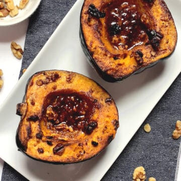 air fried acorn squash topped with honey butter and walnuts on a white plate