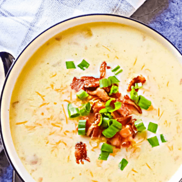 slow cooker loaded potato soup topped with bacon and chives in a white bowl