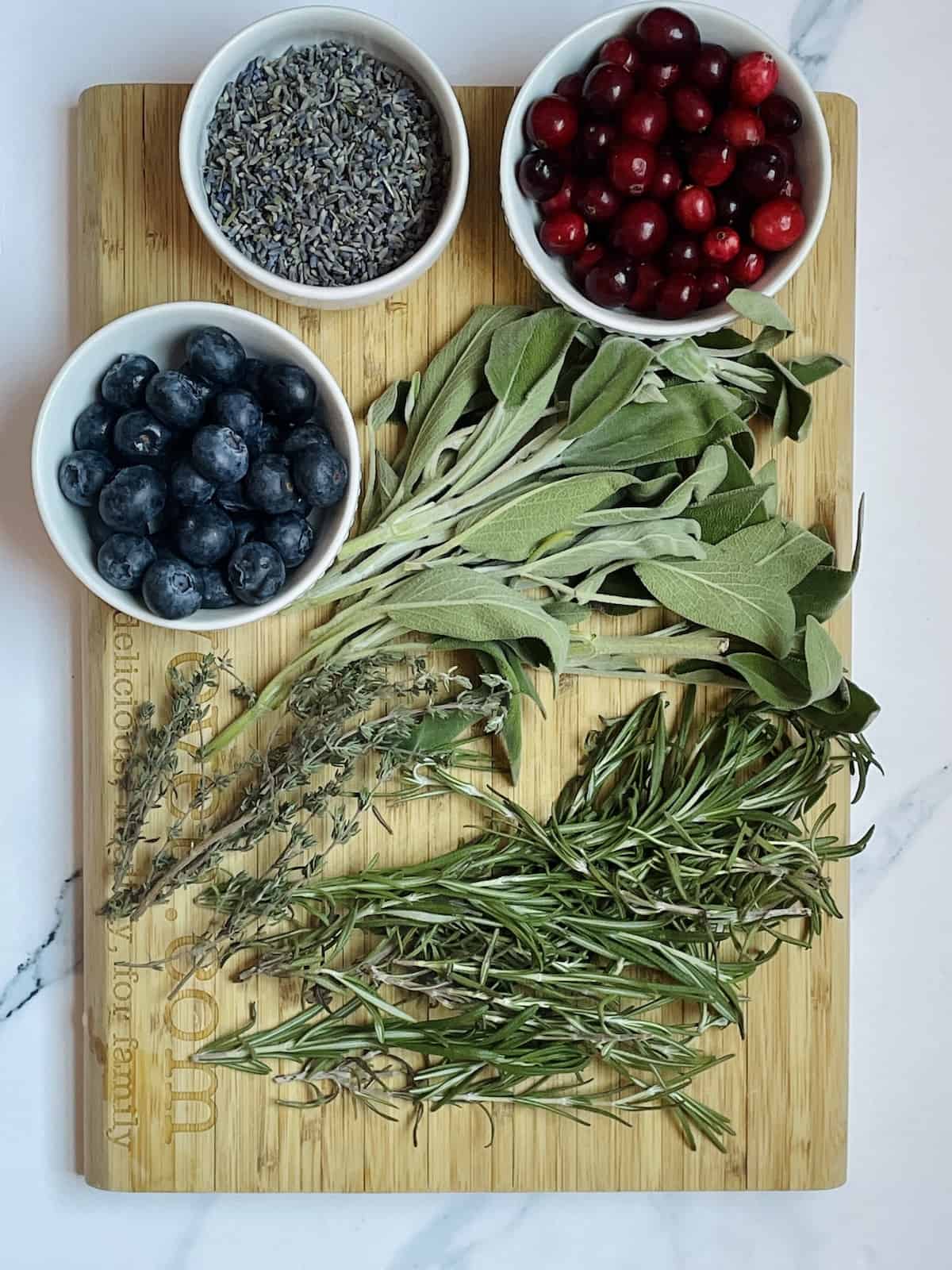 sage, rosemary, thyme, cranberries, blueberries and lavender flowers on a cutting board