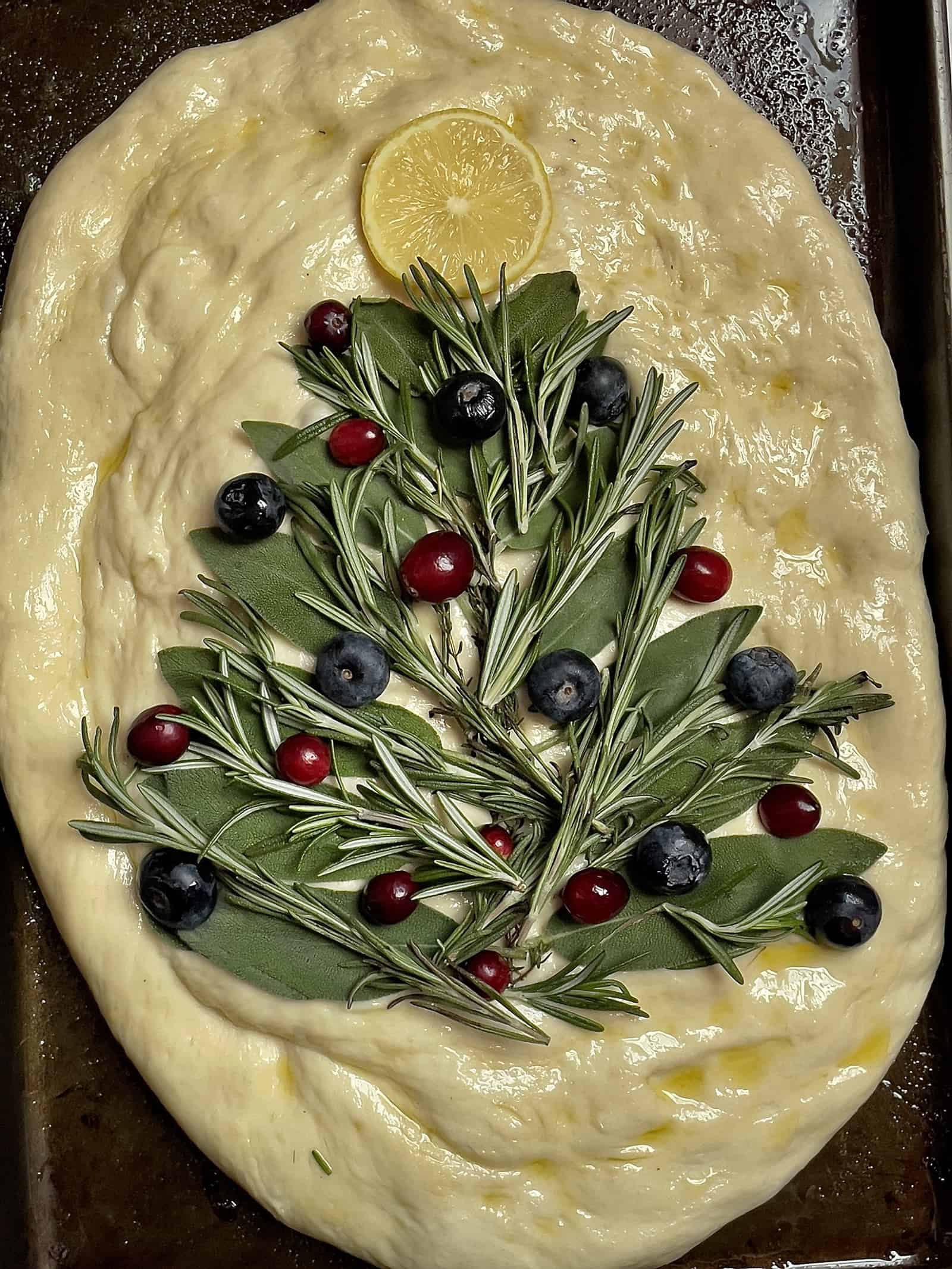 Christmas tree design on focaccia dough, with cranberry and blueberry as ornaments