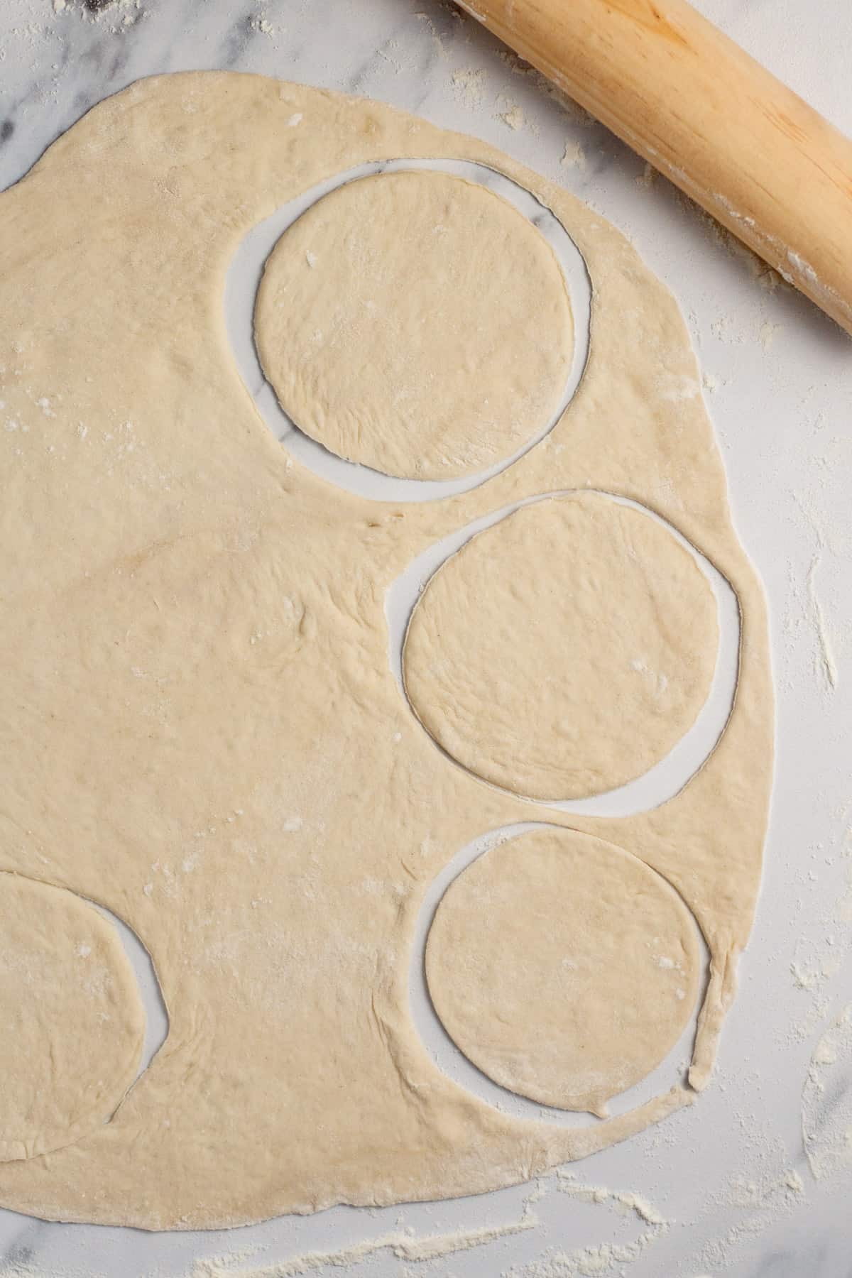 circles being cut into flattened pizza dough