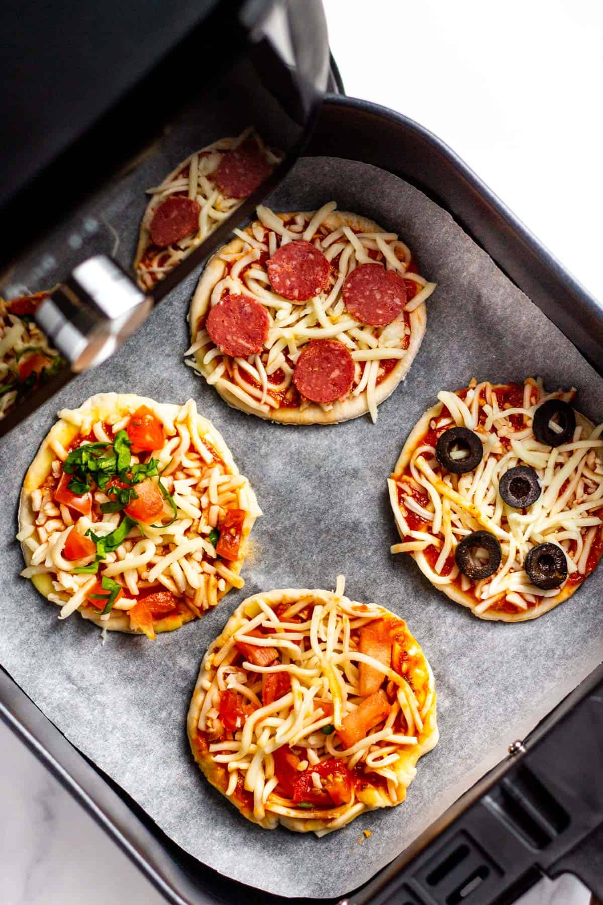 mini pizza in an air fryer basket, uncooked
