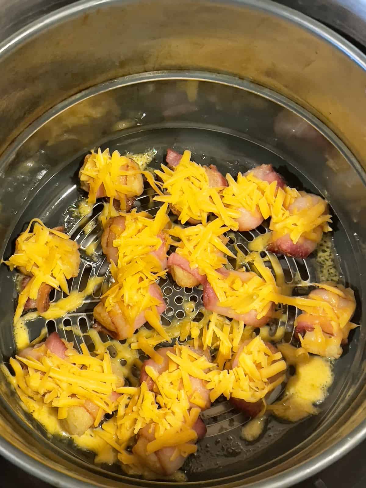 bacon wrapped tater tots in the air fryer topped with cheddar cheese
