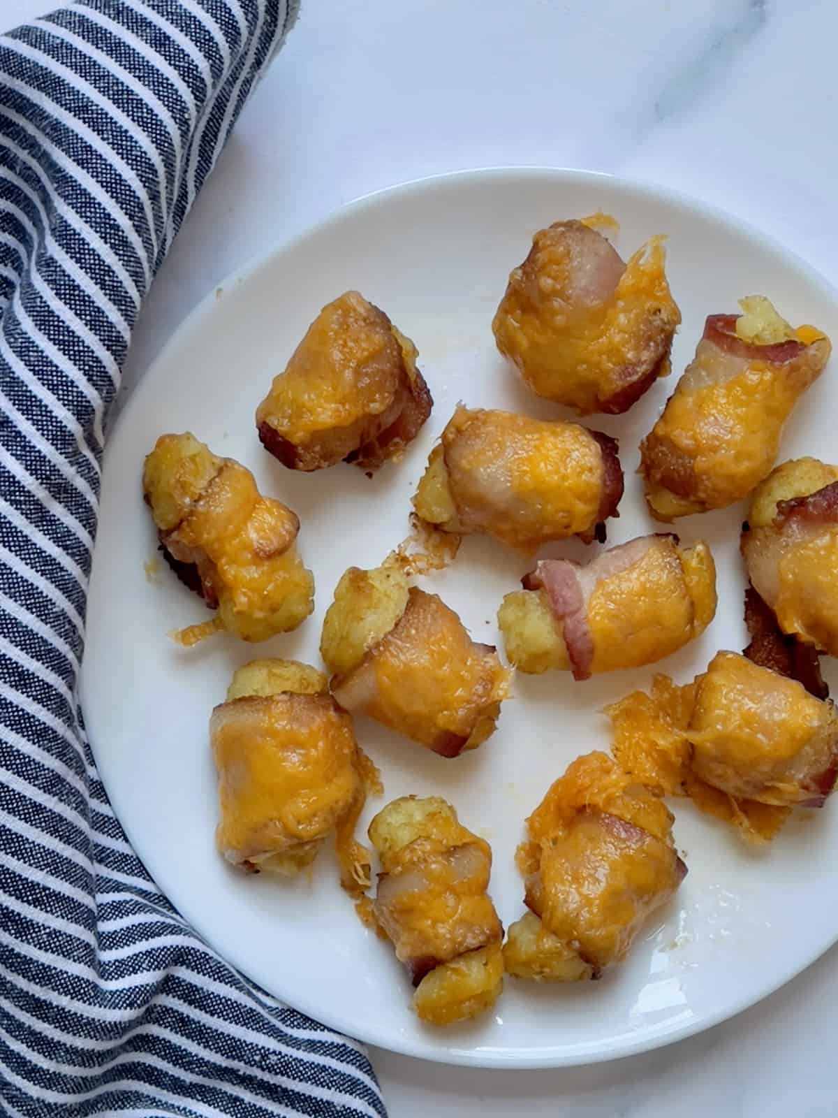 cheddar cheese topped on bacon wrapped tater tots