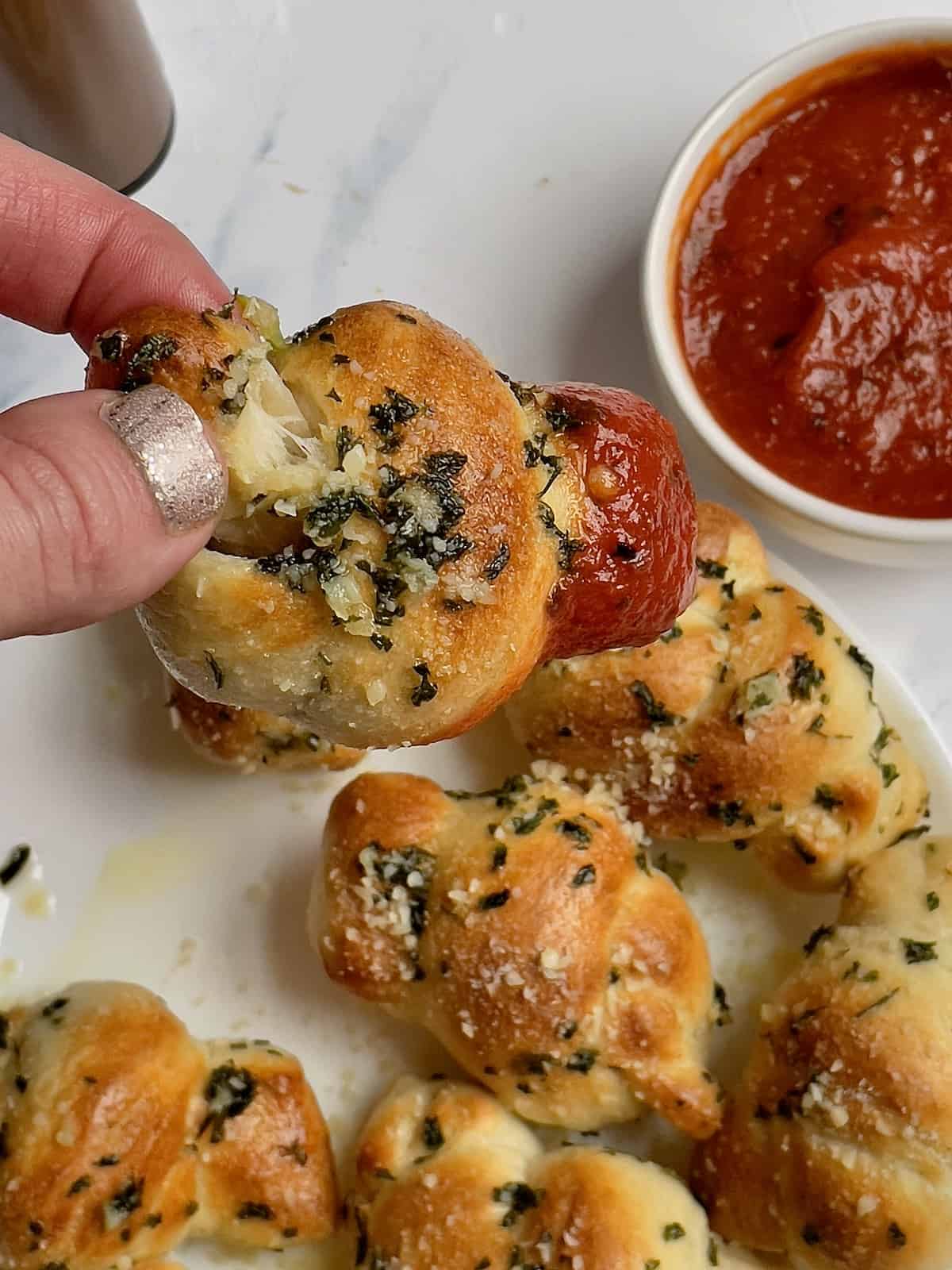 garlic knot being dipped into pizza sauce