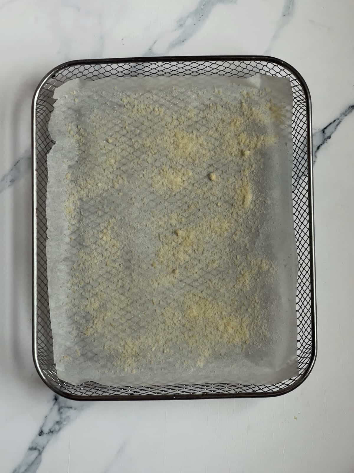 parchment paper and parmesan cheese on an air fryer basket