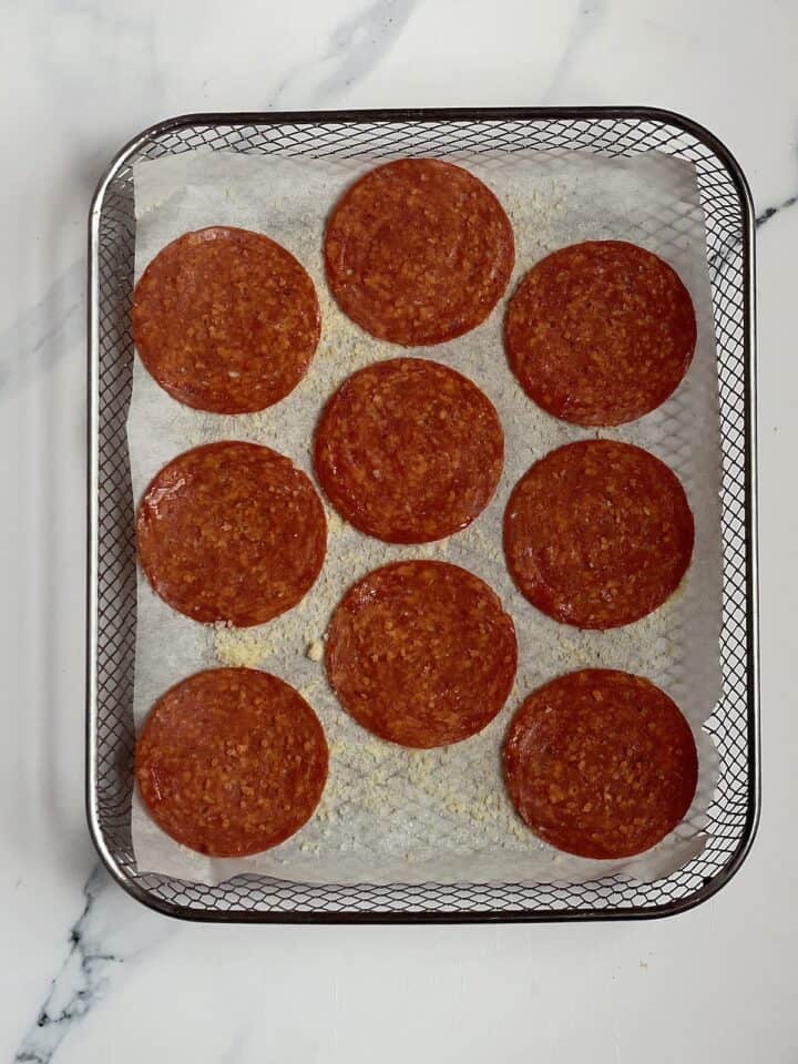 pepperoni spread out on an air fryer basket