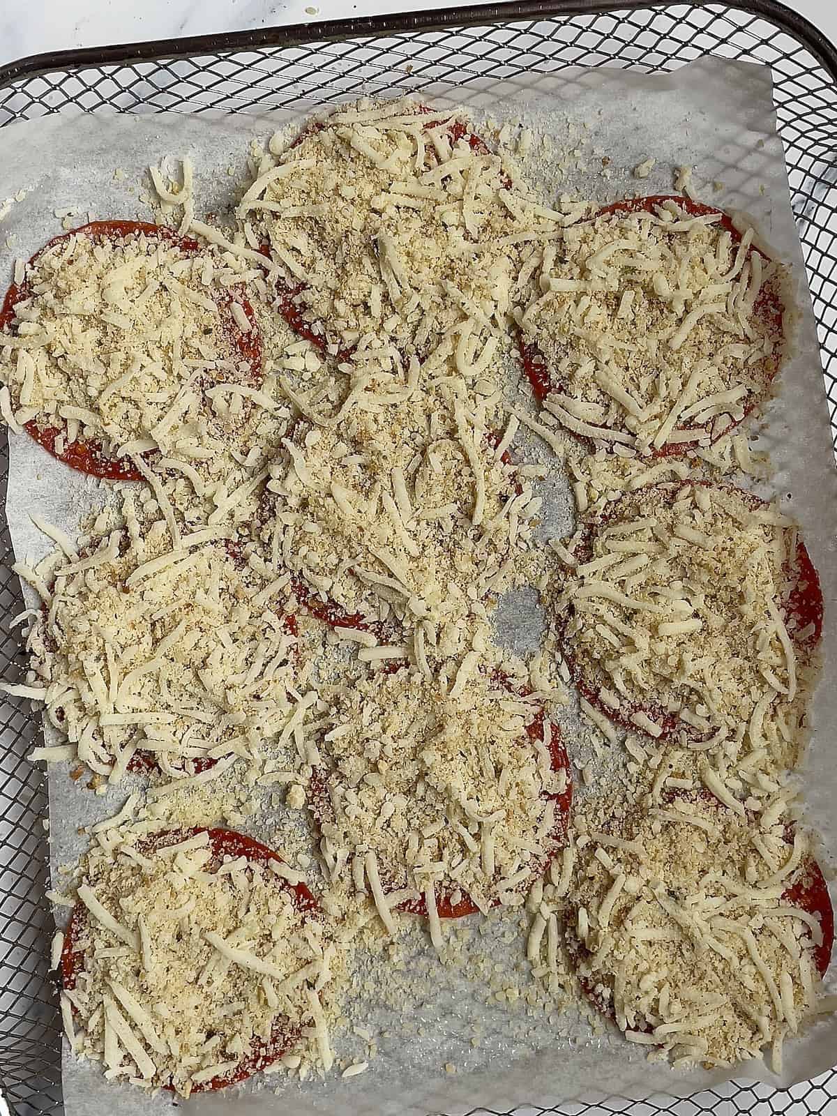 pepperoni sprinkled with mozzarella cheese in an air fryer basket