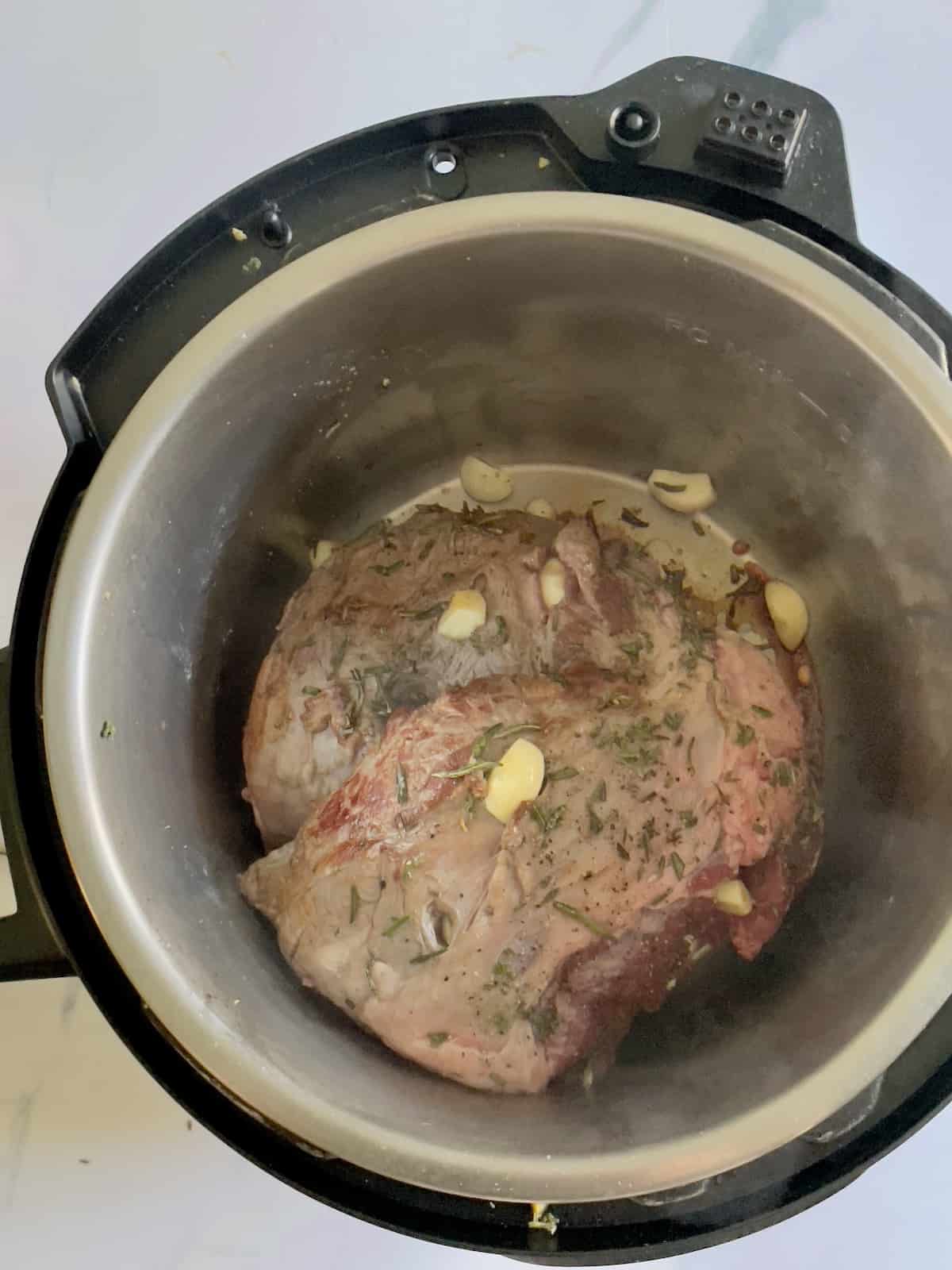 seared leg of lamb in an inner pot of a pressure cooker