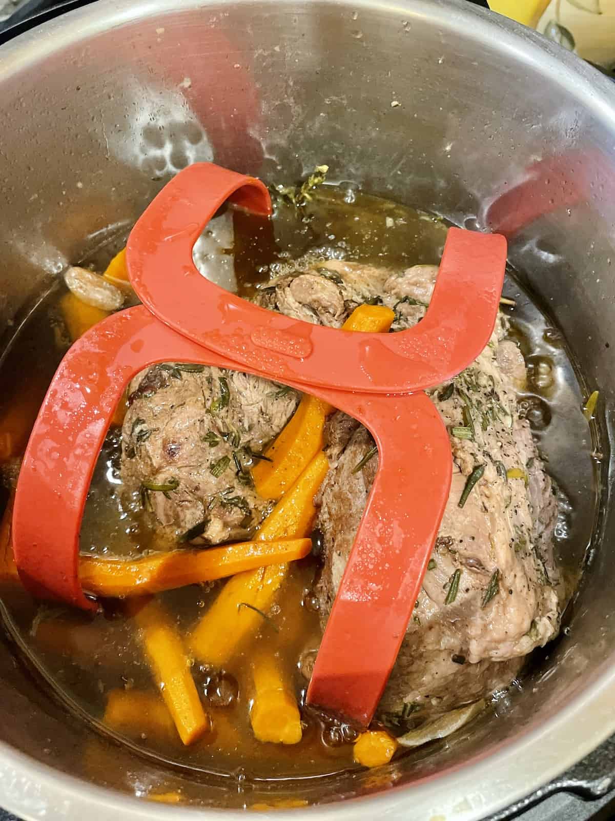 pressure cooked leg of lamb roast and carrots on a sling in the inner pot