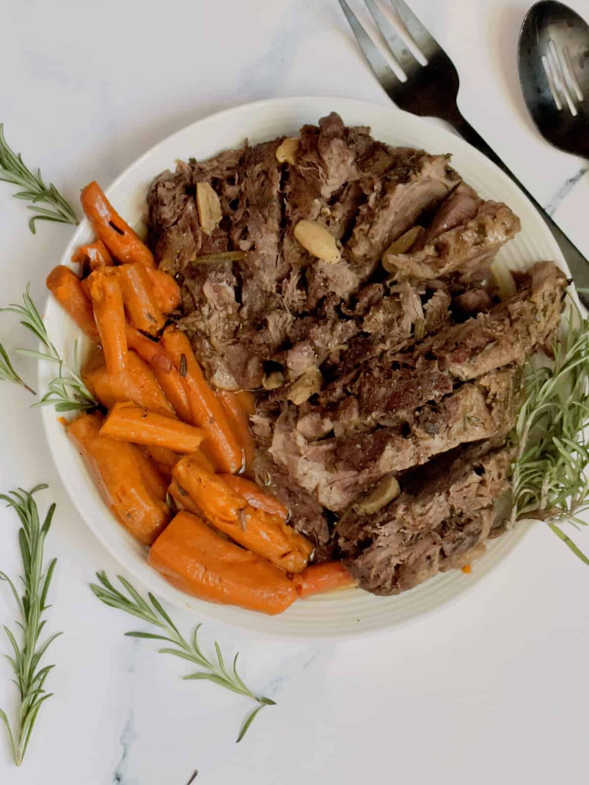 pressure cooker leg of lamb with carrots in a white serving dish