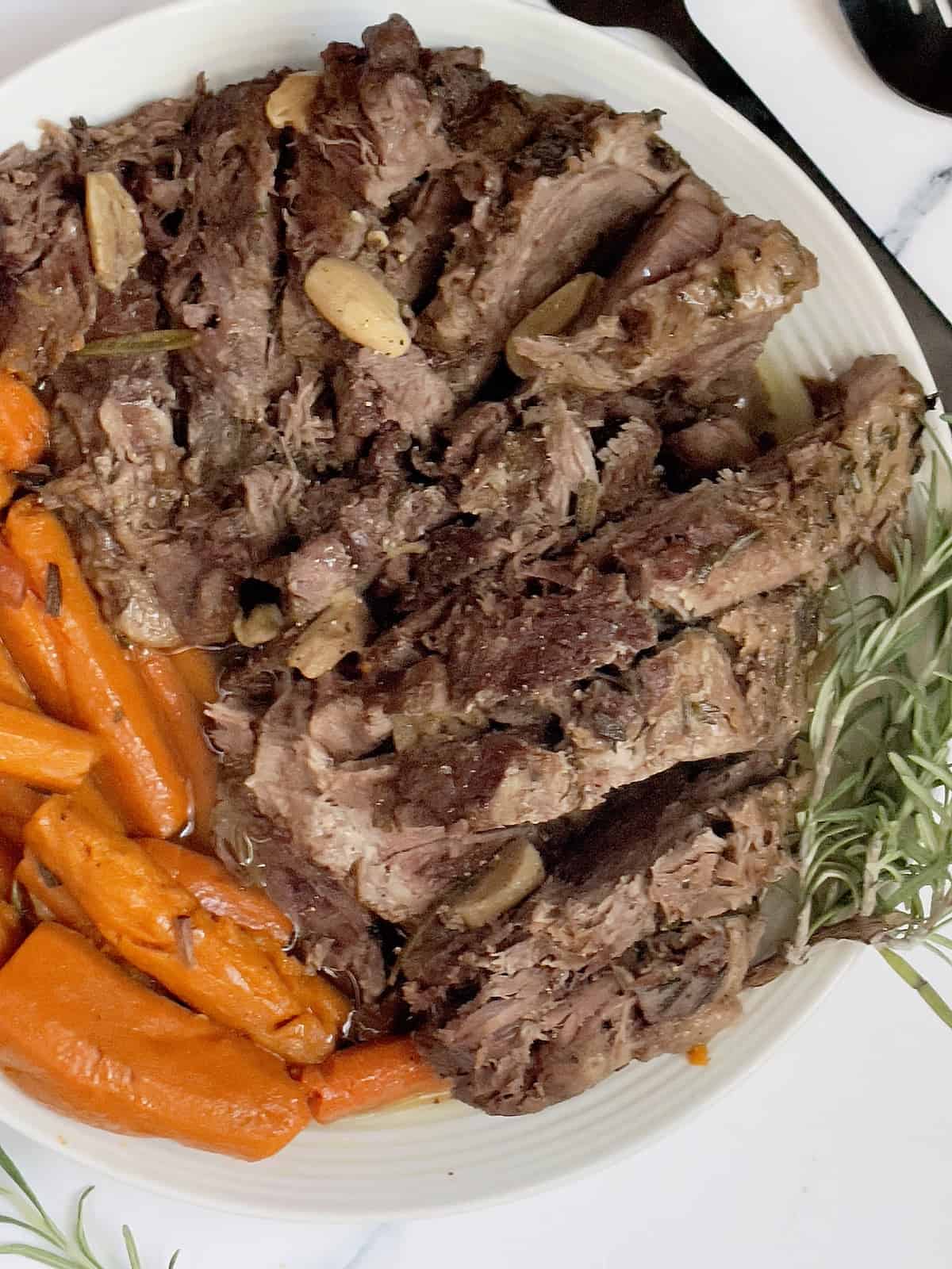 sliced pressure cooker leg of lamb on a white serving dish
