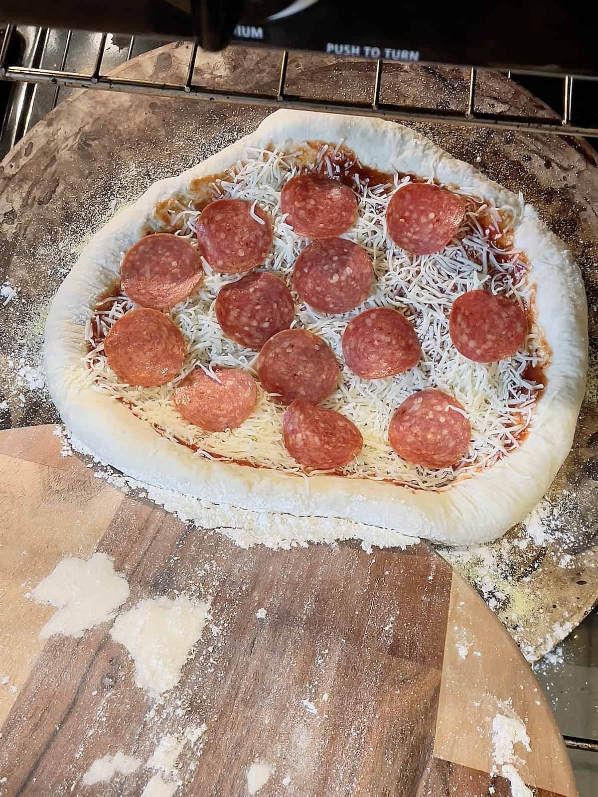 pizza being transferred onto a pizza stone in the oven