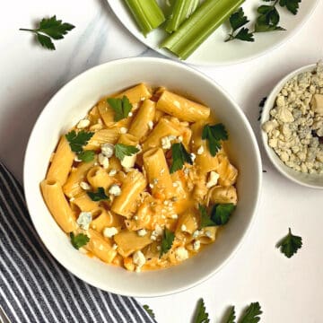 instant pot buffalo chicken pasta in a white bowl topped with blue cheese and parsley