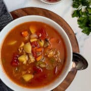instant pot manhattan clam chowder soup in a white bowl surrounded by bacon and parsley