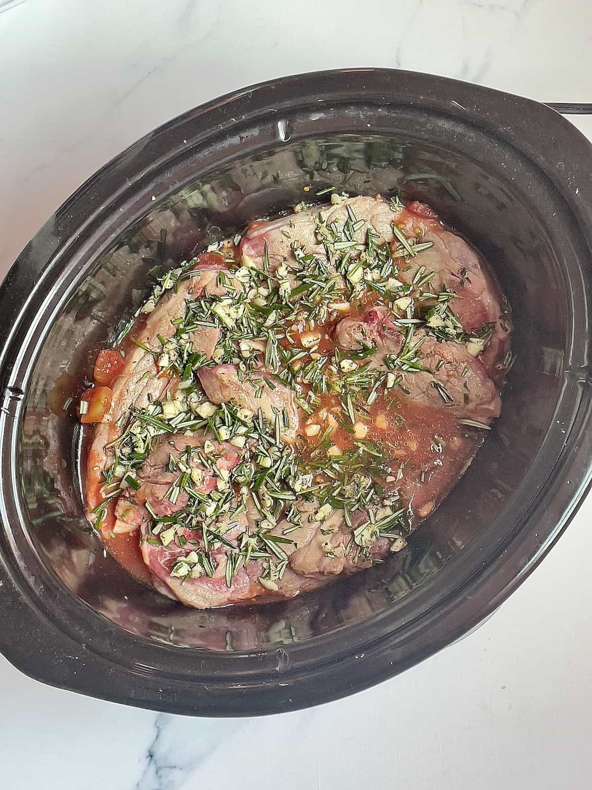 lamb, spices, seasonings, and tomatoes in a crockpot