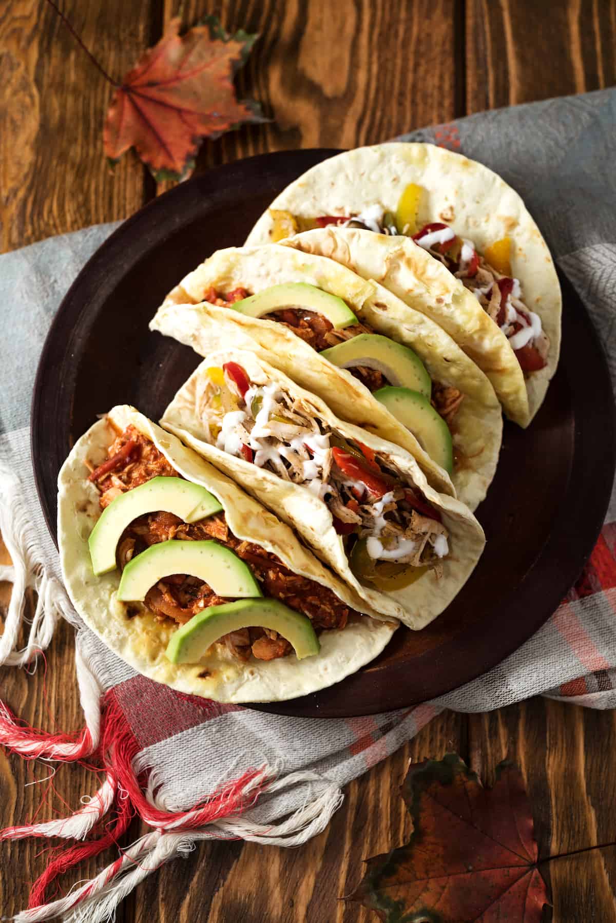 chicken tacos on a plate topped with avocado and vegetables