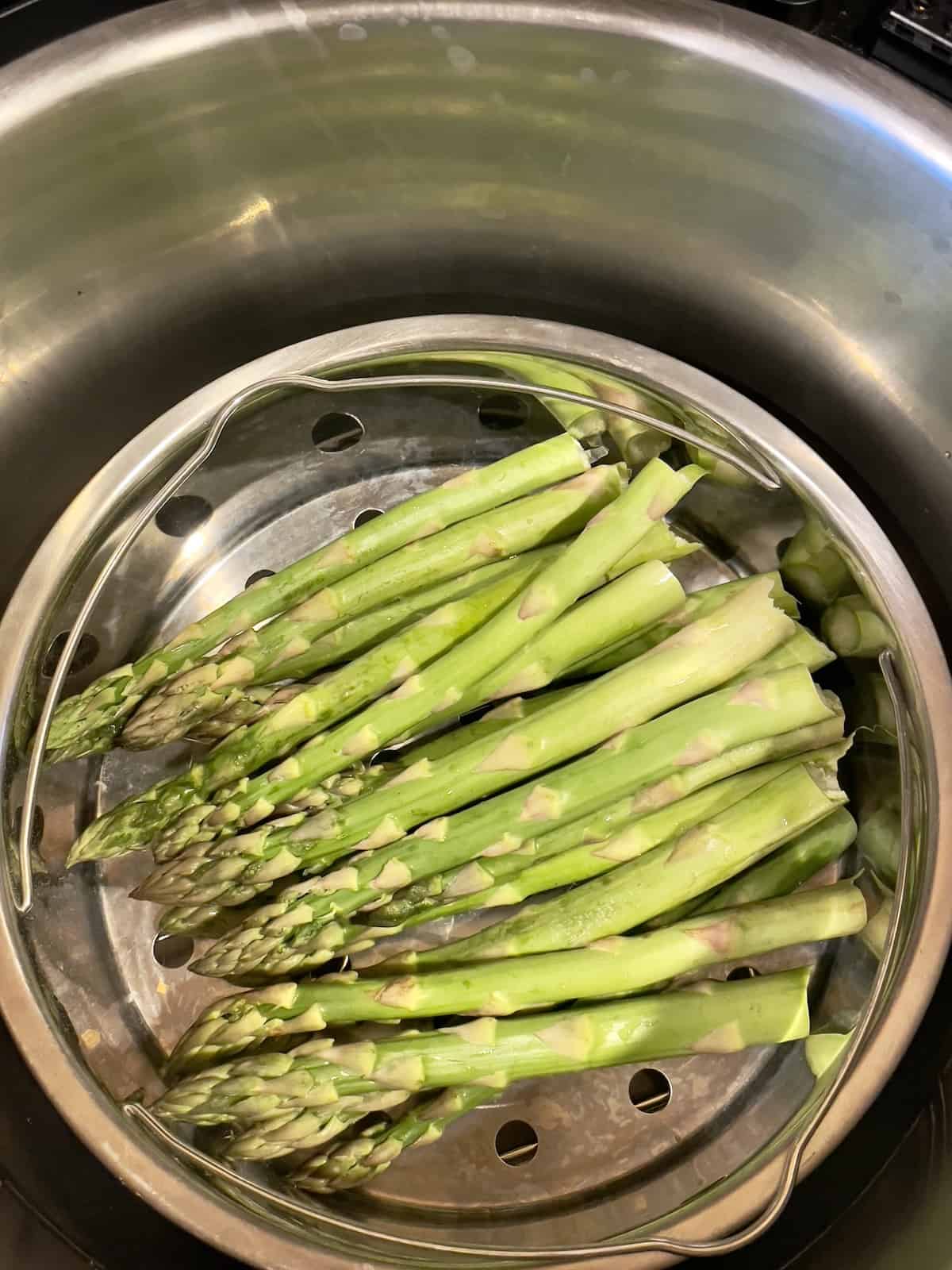 uncooked asparagus spears in the steamer basket of the instant pot