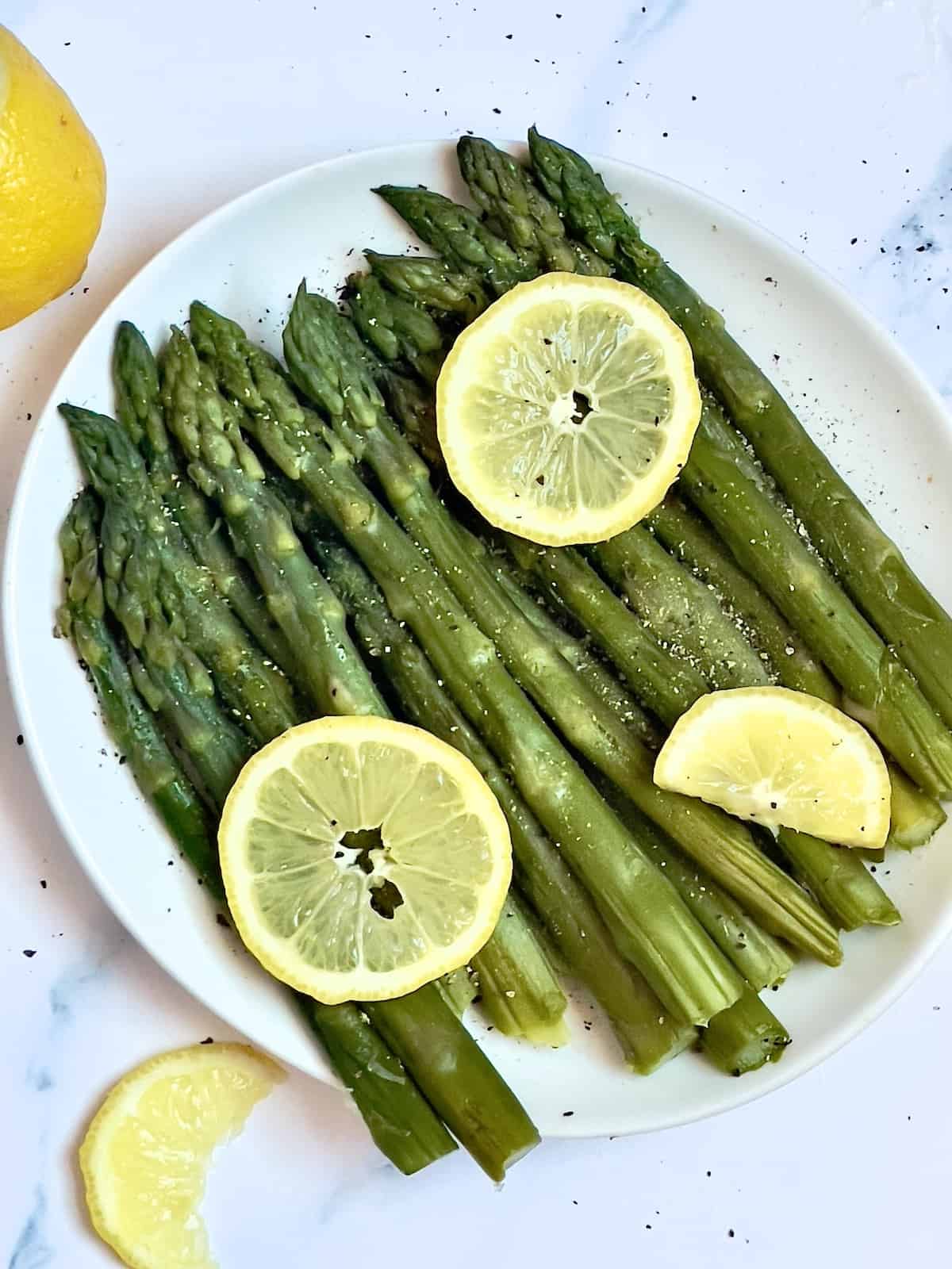 pressure cooked asparagus spears on a plate topped with lemon slices