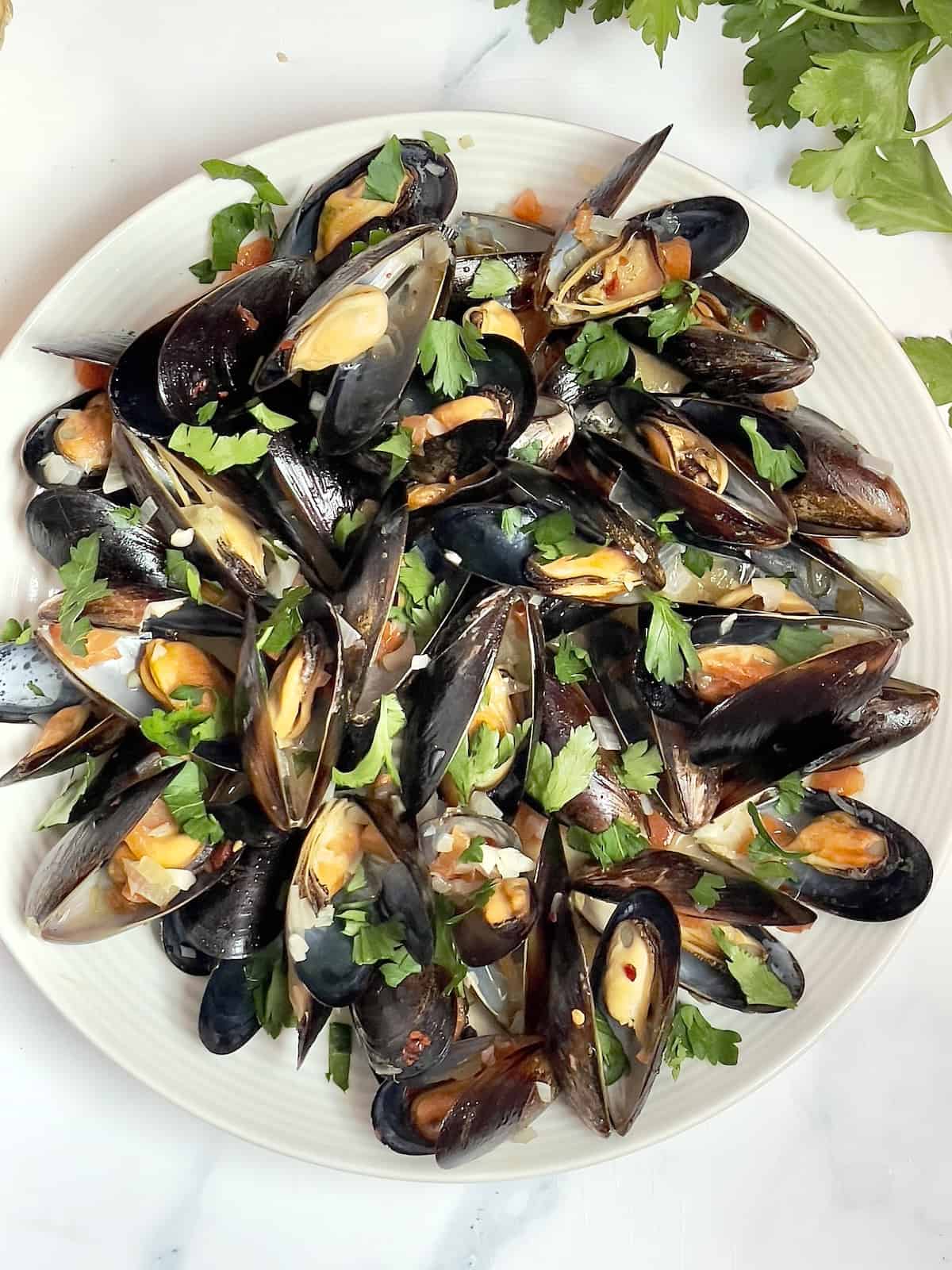 instant pot mussels mariniere on a white plate and topped with parsley